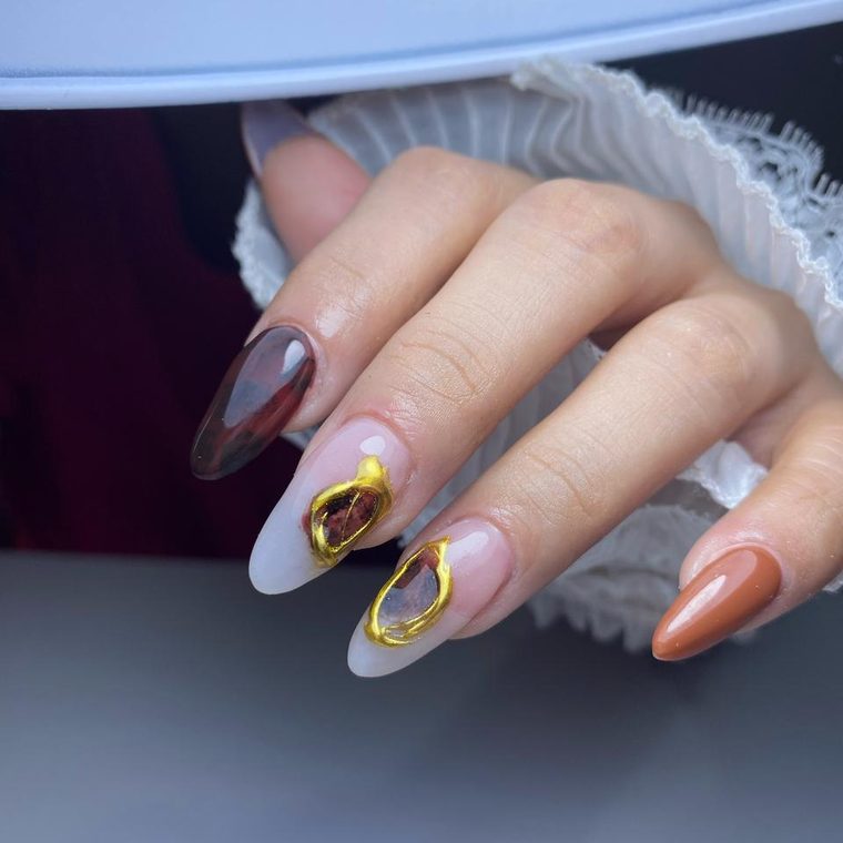 Uñas en tonos café y terracota con relieve dorado